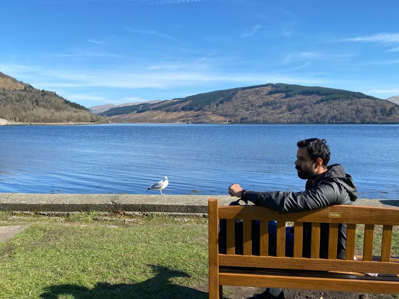 Bhunesh Sharma sitting beside a lake with hills in the background