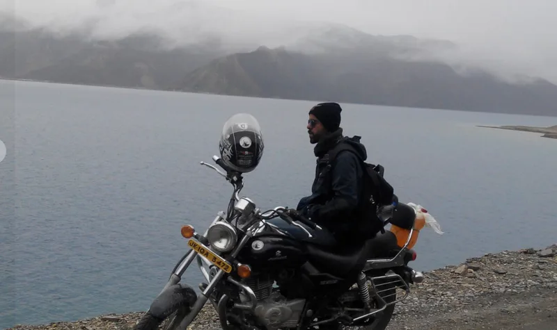 Bhunesh Sharma beside a mountain lake on his motorcycle